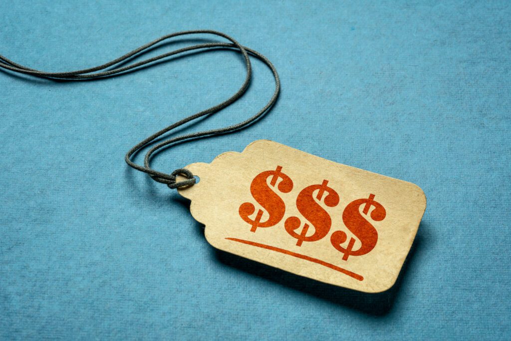 triple dollar sign - red stencil text on a paper price tag against blue paper background